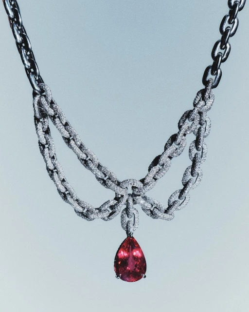 Elegant jewelry shot of a diamond encrusted, silver chain necklace with a large, tear-drop shaped, pink tourmaline pendant.