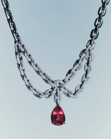 Elegant jewelry shot of a diamond encrusted, silver chain necklace with a large, tear-drop shaped, pink tourmaline pendant.
