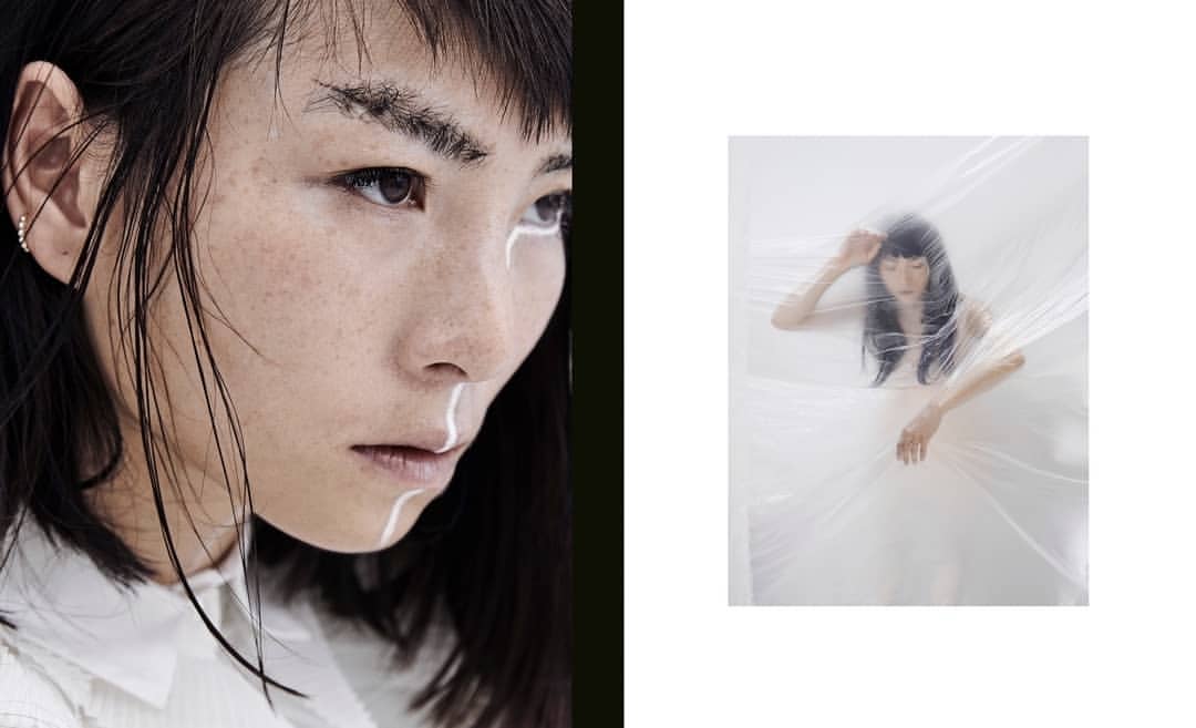 Artistic close-up and medium shot of a woman with black hair and white facial markings, partially covered in a sheer white wrap.
