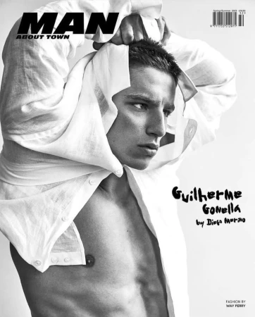 Black and white magazine cover featuring a portrait of a handsome male model wearing a partially unbuttoned white shirt.