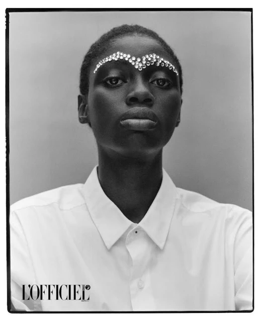 Striking black and white studio portrait of an African American woman adorned with decorative rhinestones on her forehead and wearing a white shirt.