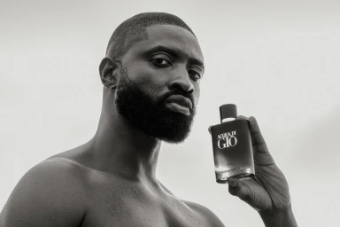Black man holding a perfume bottle in a monochrome portrait directed by Dillon Buirski