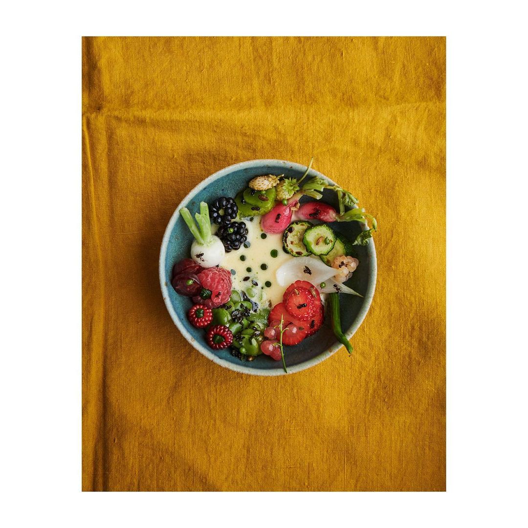 Overhead shot of a bowl of colorful salad with sliced strawberries, blackberries, radishes, green beans, and a light creamy sauce.
