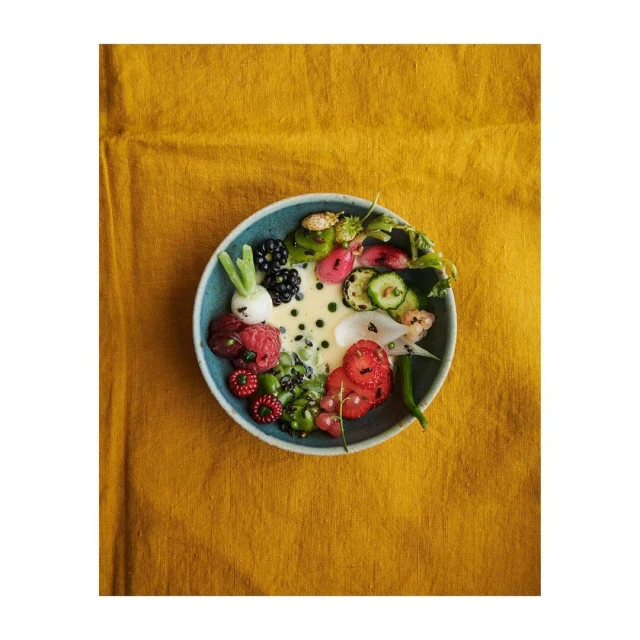 Overhead shot of a bowl of colorful salad with sliced strawberries, blackberries, radishes, green beans, and a light creamy sauce.