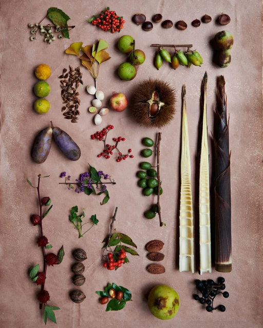 Overhead shot of assorted fruits, vegetables, nuts, and bamboo shoots arranged on a pink textured surface, showcasing autumn harvest.