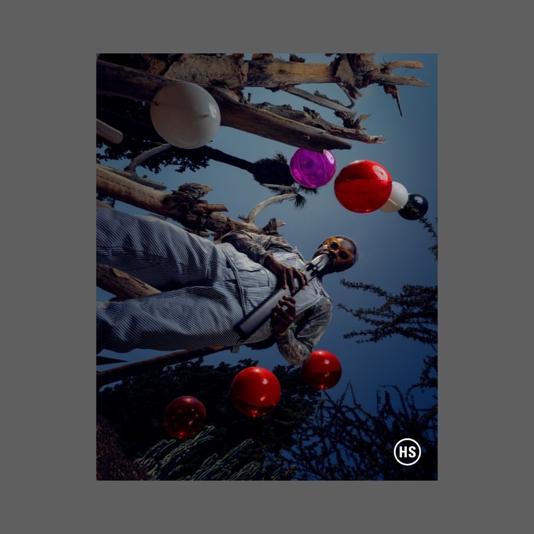 Surreal portrait of a Black adult male in overalls holding a pipe-like object, with floating red, white, purple, and black spheres in a sky setting.