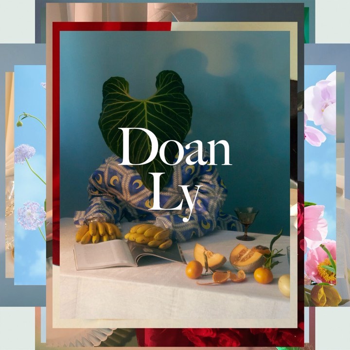 Abstract still life shot of a large green leaf positioned over a person's head, with fruit and book on a draped white table.