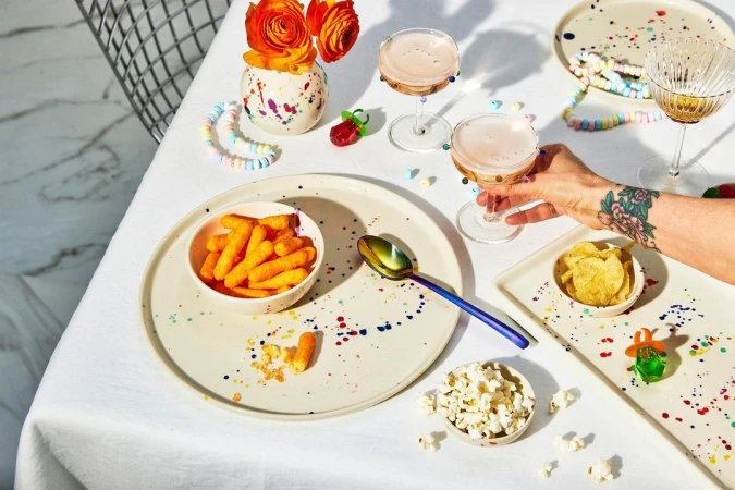 Overhead view of a table set with snacks, drinks, and colorful decorations, creating a festive and inviting atmosphere for a celebration.