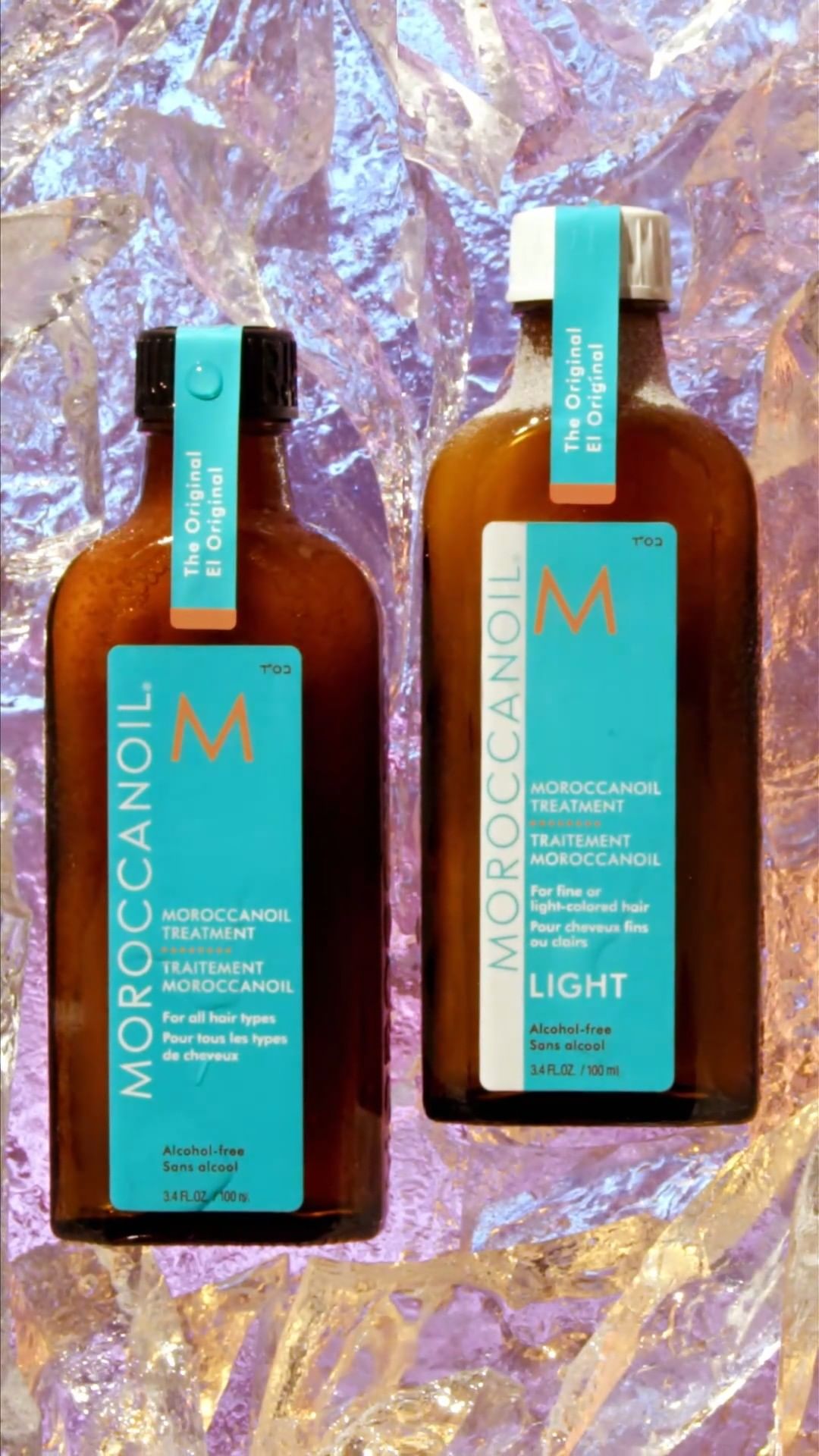 Two bottles of Moroccanoil hair treatment, one labeled “Light,” are showcased against a crinkled, reflective, light-colored background.