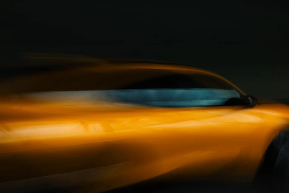 Motion blur image of a yellow car with a sleek design against a dark background. Automotive photography with a sense of speed.