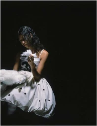 A woman holding fluffy white material in a low-key portrait by photographer Dorothy Sing Zhang