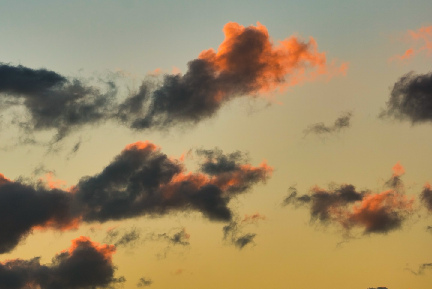 Dramatic sky with dark clouds and a bright orange glow during sunset or sunrise, creating a stunning natural vista.