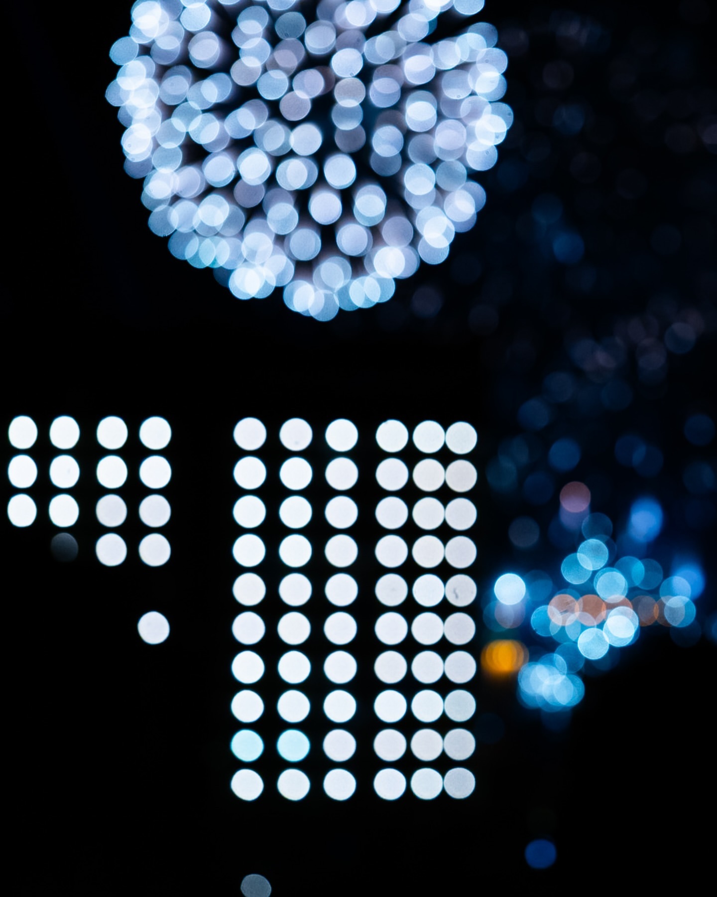 Abstract bokeh effect featuring arranged white and blue lights against a dark background, creating a modern and artistic visual.
