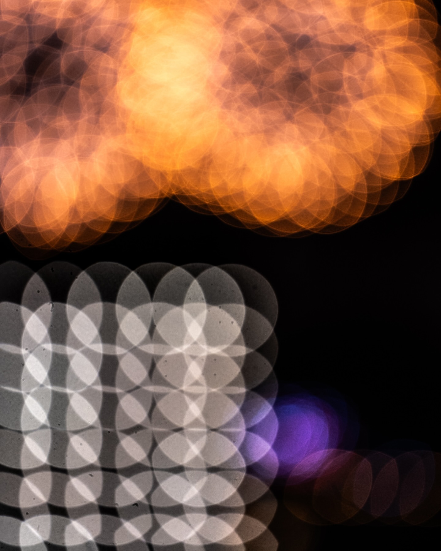 Abstract image of blurred lights with orange lights at the top and white lights arranged in a grid pattern at the bottom.