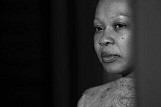 Close-up monochrome portrait of a Black woman looking thoughtfully off-camera, photographed by Doug Menuez