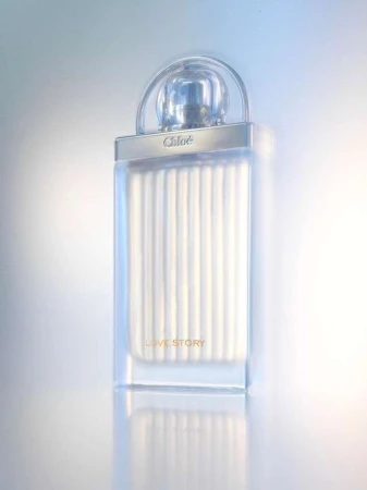 Chloé Love Story fragrance bottle with transparent cap and ribbed details, set against a soft, gradient background in a studio shot.