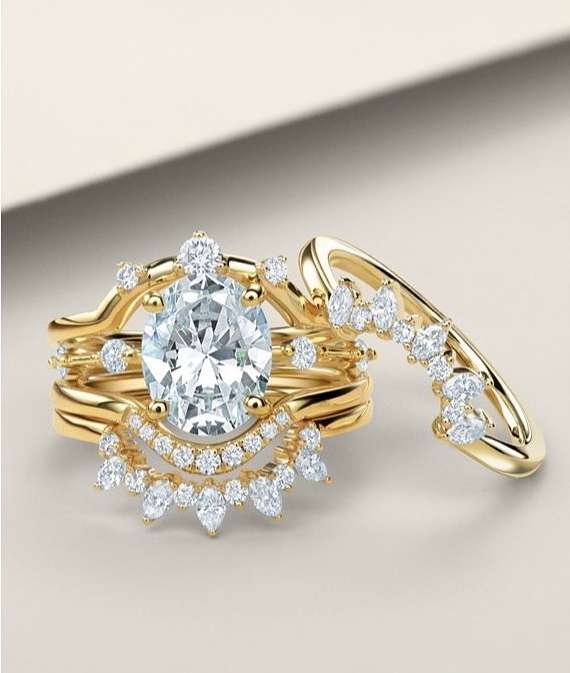 Close-up of an elegant yellow gold diamond bridal ring set featuring a large oval-cut center stone surrounded by smaller diamonds.