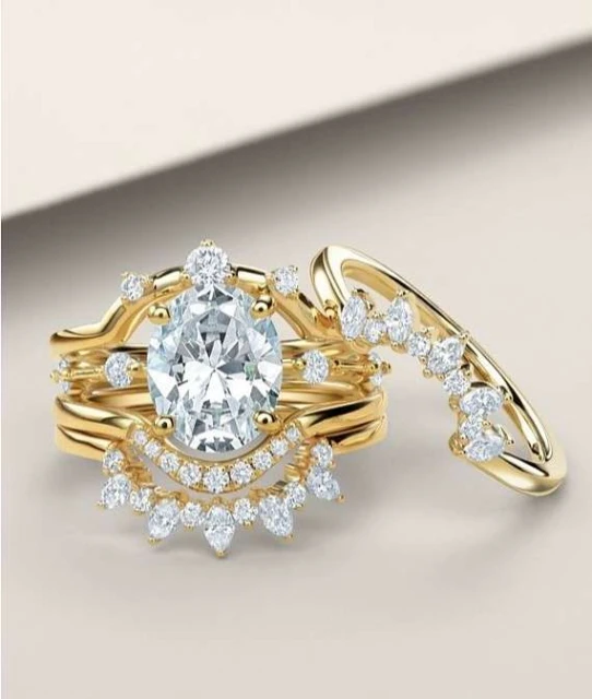 Close-up of an elegant yellow gold diamond bridal ring set featuring a large oval-cut center stone surrounded by smaller diamonds.