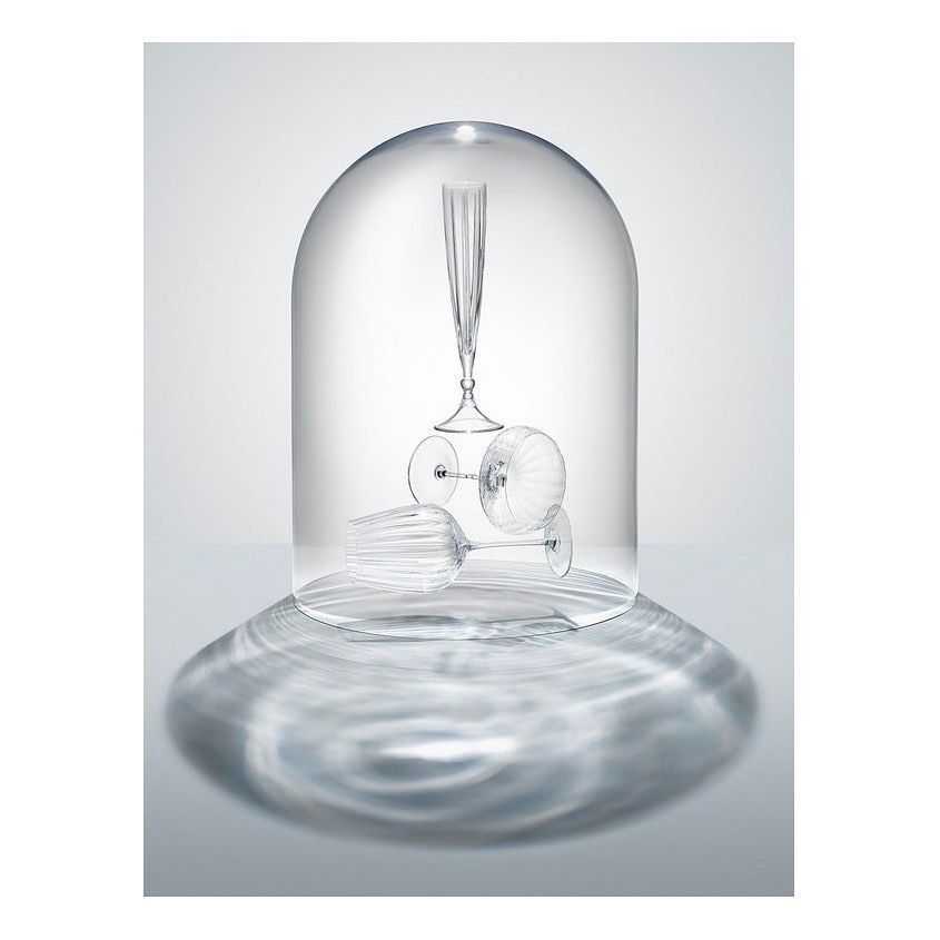 Three clear ribbed wine glasses, one flute, displayed upside down, under a clear cloche dome, creating a pattern of light and shadow.
