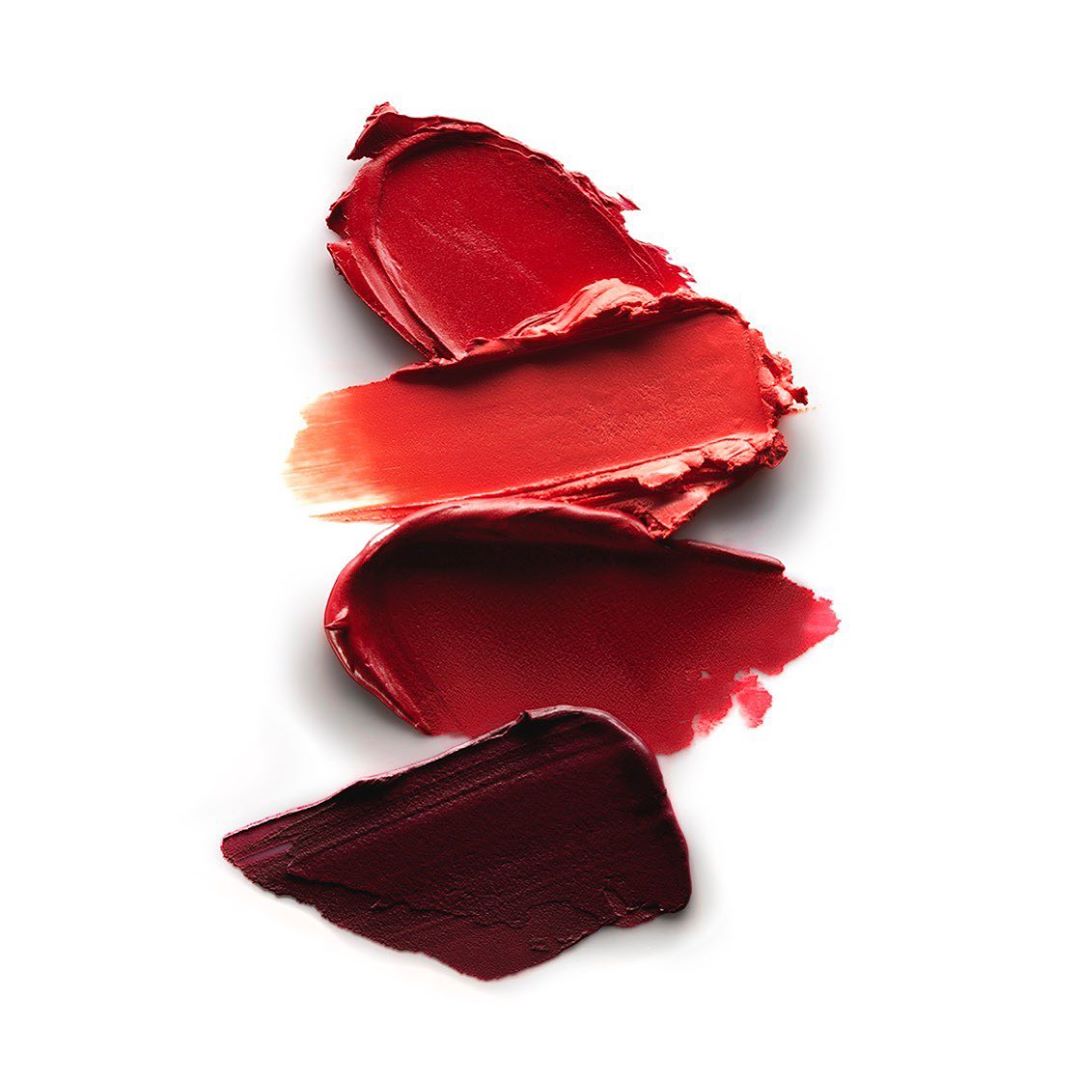 Lipstick swatches in shades of red, burgundy, and coral on a white background, showcasing textures and tones for beauty and cosmetics.