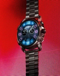 Close-up of a dark metallic smart watch with a digital blue face against a bright red dotted screen background.