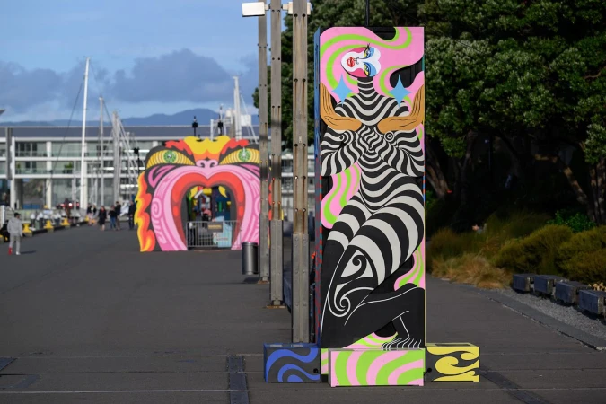 Outdoor art installation featuring a black and white striped figure and heart-shaped archway in the background, set in an urban environment.