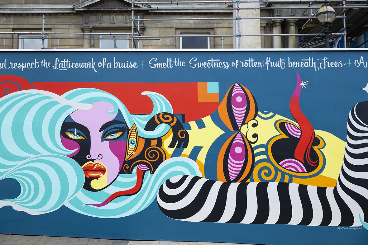 Vibrant mural on a teal background features an abstract portrait with turquoise hair and geometric shapes in orange, red, yellow, and black.