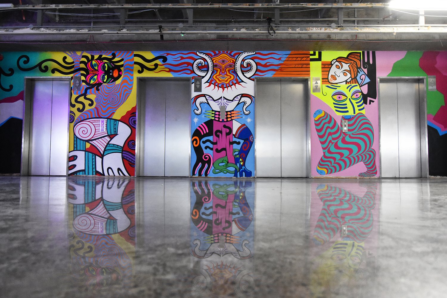 Elevator doors with colorful abstract mural art featuring human-like figures in shades of yellow, pink, blue, and black.
