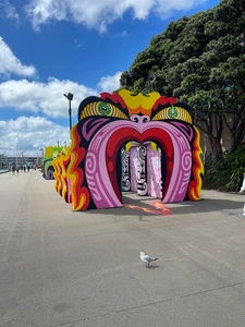 Colorful decorative outdoor installation with large painted dragon eyes and archway on concrete pathway