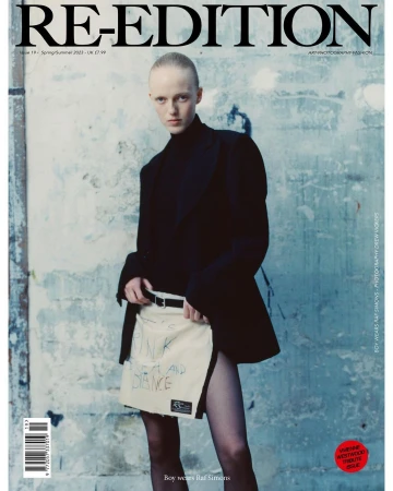 Fashion magazine cover featuring a model in a black top and unique skirt, set against a textured wall with bold magazine typography.