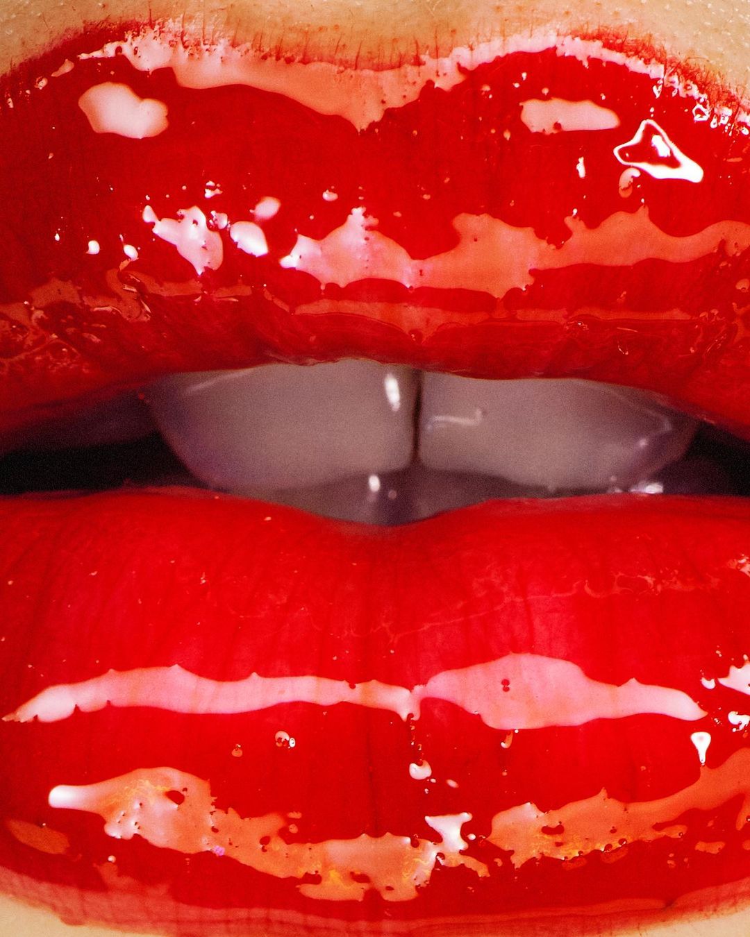 Close-up of red lips with glossy lipstick, highlighting the mouth and teeth. Beauty shot, showcasing makeup and dental aesthetics.
