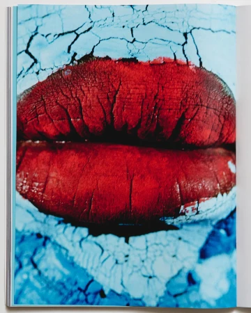 Close-up macro shot of chapped red lips against a cracked light blue textured background