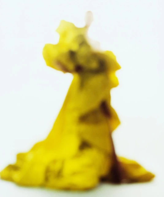 Abstract macro shot of a yellow object or substance against a white background, creating an otherworldly, blurred effect.