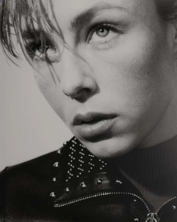 Monochrome portrait of a young woman with short blonde hair and a studded leather jacket against a neutral background, studio lighting.