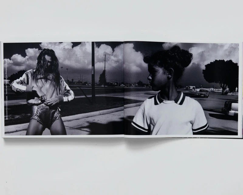 Black and white photograph featuring a fair-skinned young adult and an African-American child in an outdoor, urban setting, seemingly captured from a book.