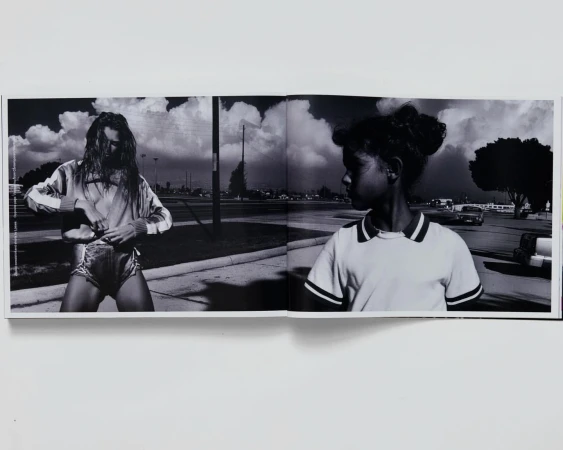 Black and white photograph featuring a fair-skinned young adult and an African-American child in an outdoor, urban setting, seemingly captured from a book.