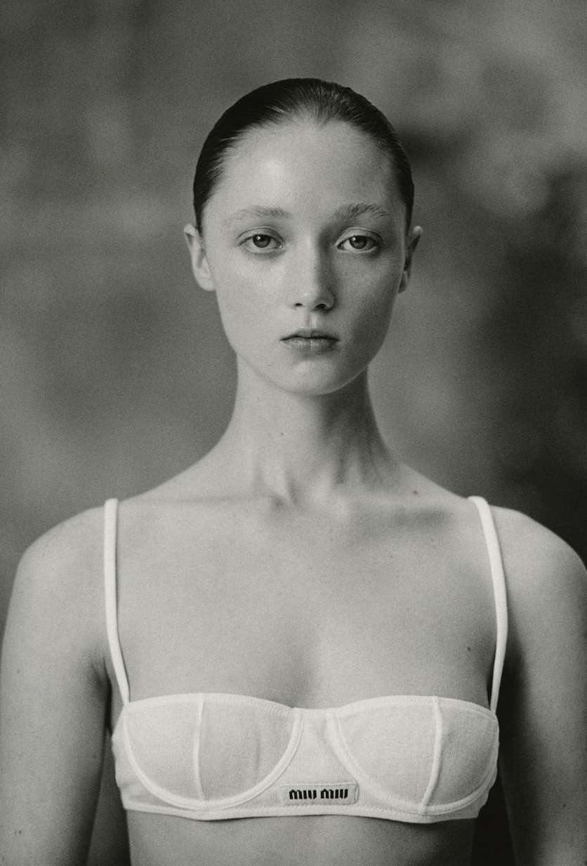 Portrait of a woman with slicked-back dark hair wearing a white bra top photographed in monochrome film grain by Drew Vickers