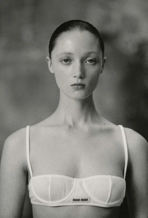 Portrait of a woman with slicked-back dark hair wearing a white bra top photographed in monochrome film grain by Drew Vickers