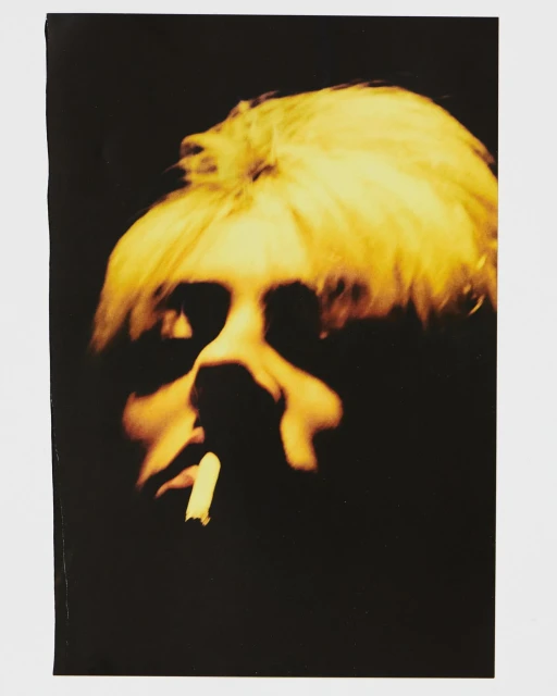 Portrait of adult male with blonde hair smoking, on a black background. Visible is head and shoulders, facing camera in a close-up.