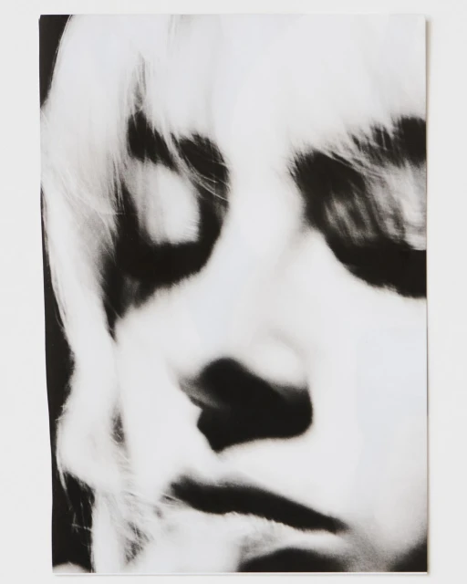 Monochrome portrait of a person with fair hair, featuring high contrast and a close-up view emphasizing facial details and texture.