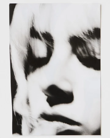 Monochrome portrait of a person with fair hair, featuring high contrast and a close-up view emphasizing facial details and texture.