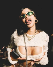 Woman wearing gold-rimmed sunglasses, layered necklaces, and a cream open-knit top by photographer Dune Tilley in Cape Town.