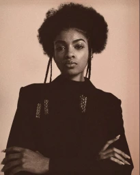 Portrait of a black woman with a rounded afro hairstyle wearing a dark jacket with braided hair strands by Dune Tilley.