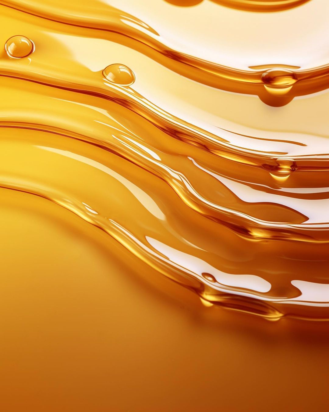 Abstract close-up of flowing, viscous liquid in shades of amber and gold, creating a sense of depth and movement with small drops.
