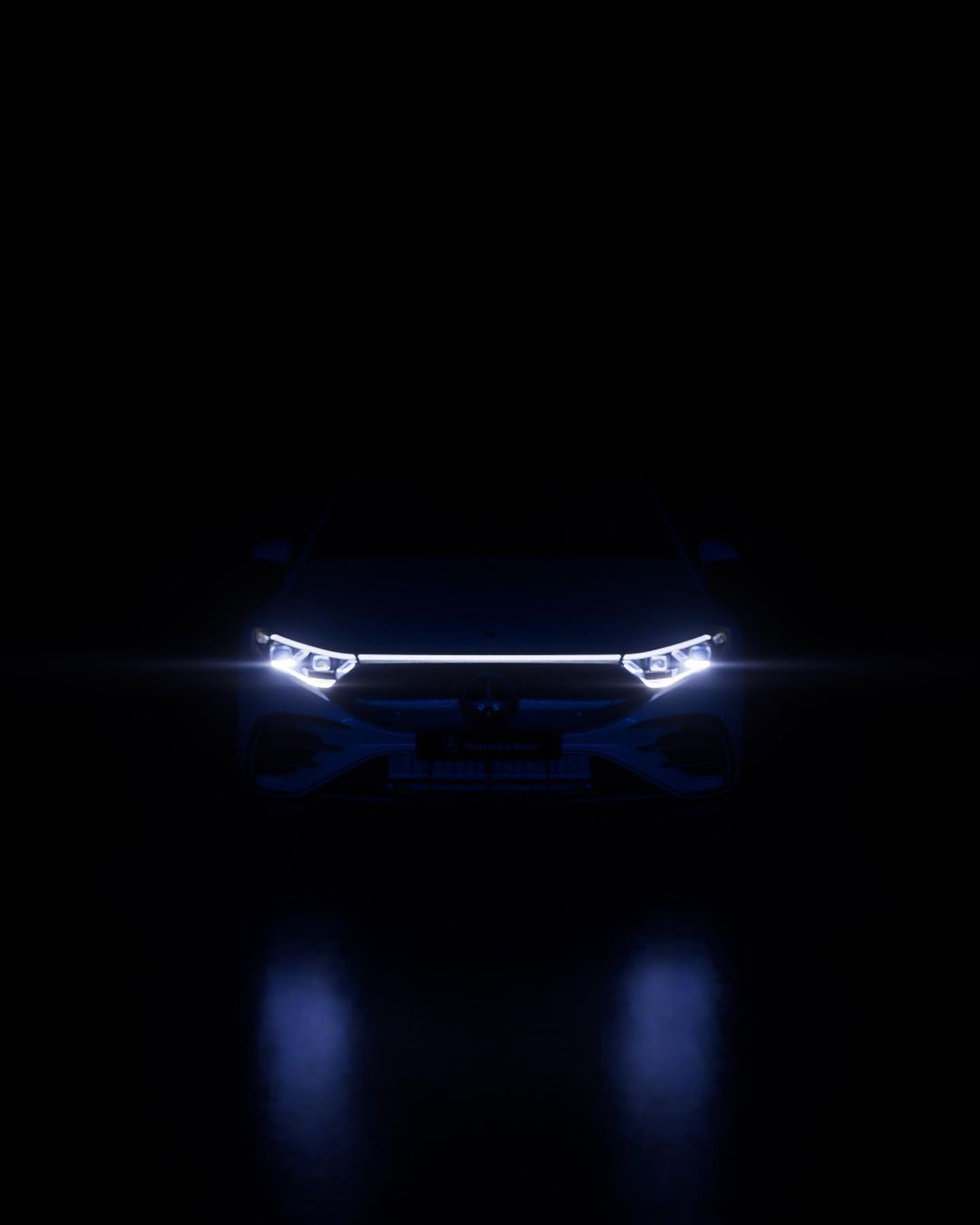 Front view of a car with illuminated headlights and grill in a dark setting, creating a sense of mystery and highlighting the vehicle's design.