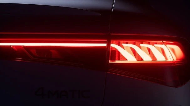 Close-up of a Mercedes-Benz car taillight, highlighting the intricate LED design with horizontal and angled light bars against a dark backdrop.