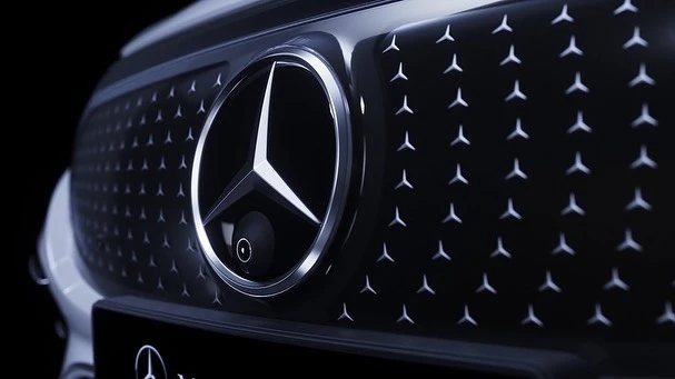 Close-up of a black Mercedes-Benz grille with a large, three-pointed star logo, surrounded by smaller, star-shaped elements.