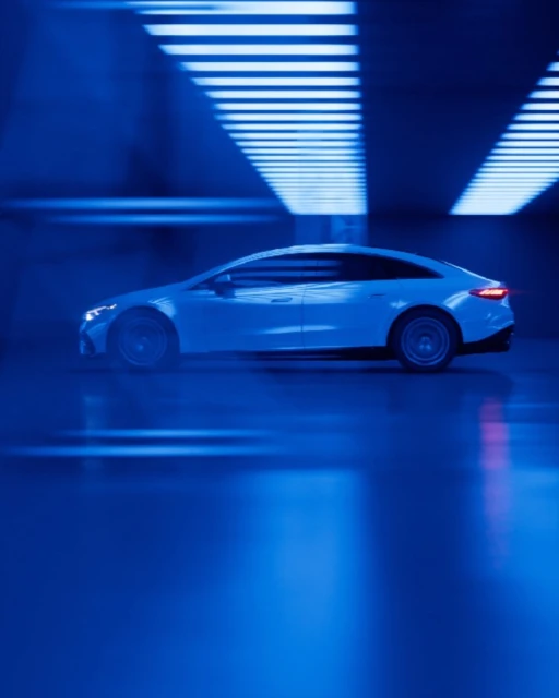 Sleek white electric car in motion, side view, displayed against a backdrop of bright blue neon lights. Automotive concept.