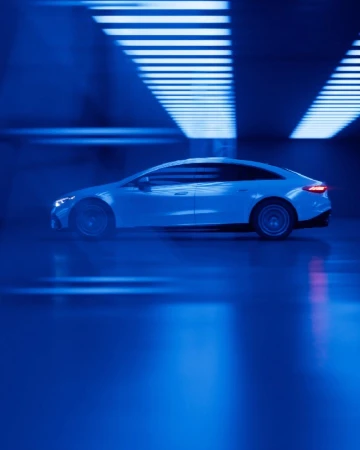 Sleek white electric car in motion, side view, displayed against a backdrop of bright blue neon lights. Automotive concept.