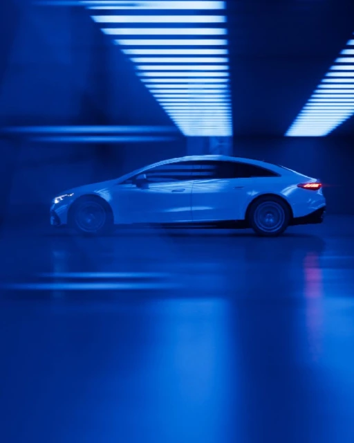 Sleek, white electric car showcased in a modern, blue-lit environment, highlighting its aerodynamic design and contemporary aesthetic.